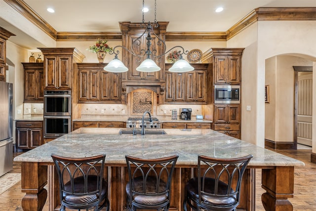 kitchen with light stone counters, decorative light fixtures, a large island, and appliances with stainless steel finishes