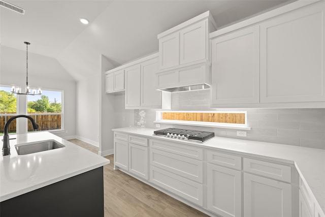 kitchen with a notable chandelier, white cabinetry, stainless steel gas stovetop, and vaulted ceiling