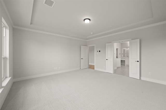 unfurnished bedroom with ornamental molding, light carpet, connected bathroom, and a raised ceiling