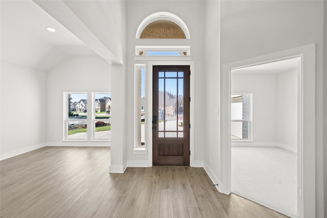 foyer with plenty of natural light, vaulted ceiling, and light hardwood / wood-style flooring