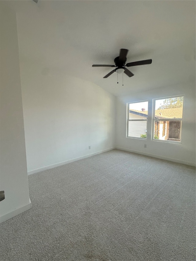 spare room with ceiling fan, vaulted ceiling, and light colored carpet