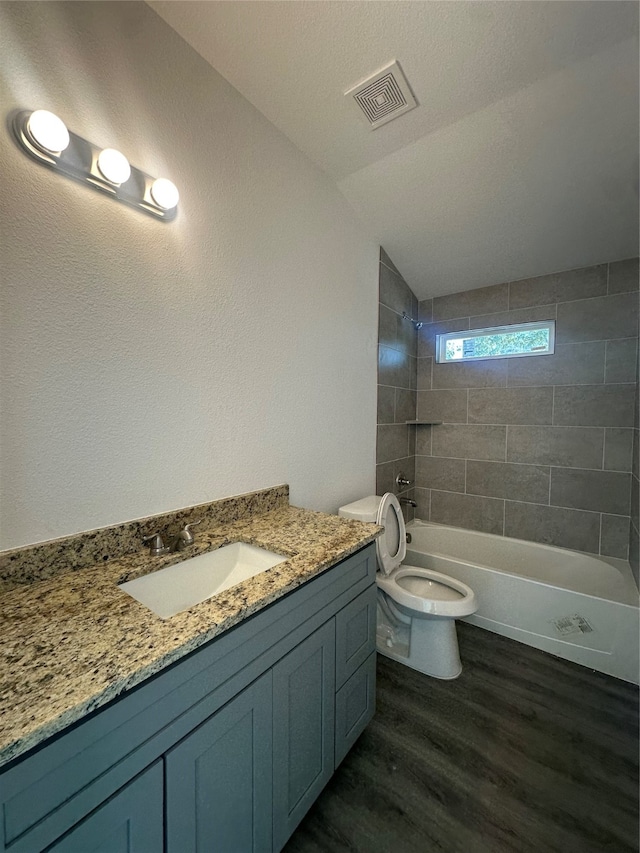 full bathroom with tiled shower / bath, wood-type flooring, vaulted ceiling, toilet, and vanity