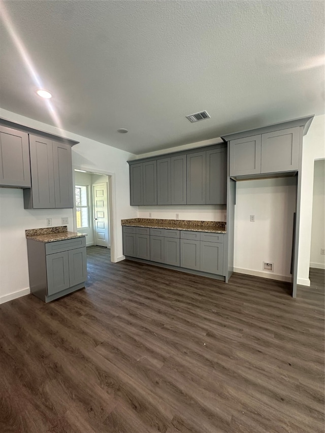 kitchen with a textured ceiling, dark hardwood / wood-style floors, and gray cabinets