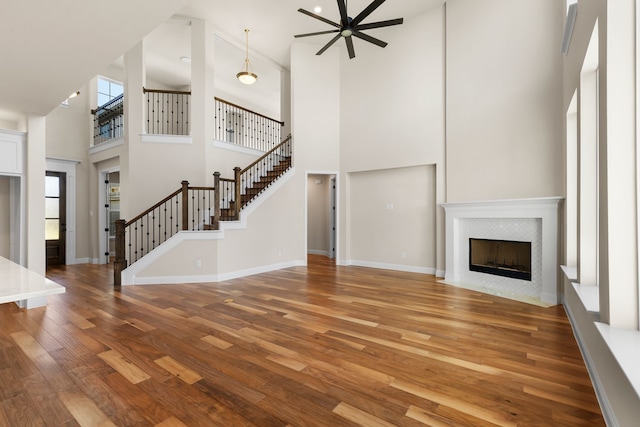 unfurnished living room featuring high vaulted ceiling, wood-type flooring, ceiling fan, and a fireplace