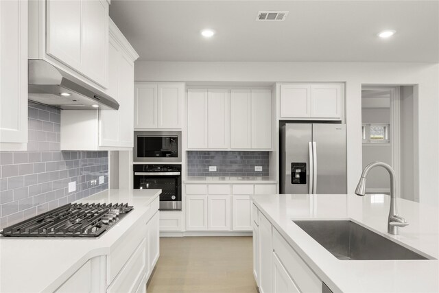 1008 Roys Dr, Rockwall, TX 75087 - kitchen with stainless steel appliances, a sink, under cabinet range hood, backsplash, and light countertops