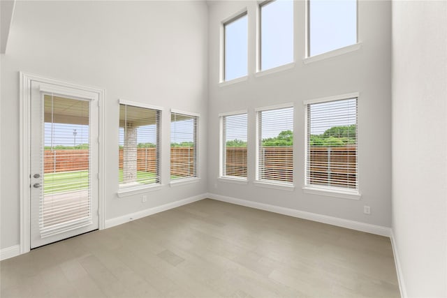 1008 Roys Dr, Rockwall, TX 75087 - unfurnished sunroom featuring a towering ceiling, healthy amount of natural light, baseboards, and wood finished floors