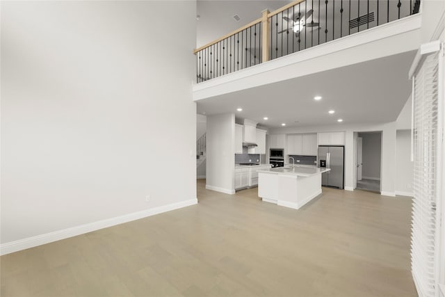 1008 Roys Dr, Rockwall, TX 75087 - unfurnished living room featuring a high ceiling, light wood-style flooring, recessed lighting, and baseboards