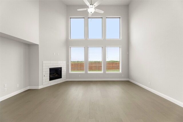 1008 Roys Dr, Rockwall, TX 75087 - unfurnished living room with wood finished floors, a ceiling fan, baseboards, plenty of natural light, and a high ceiling