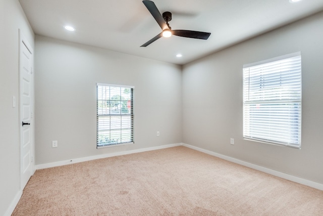 empty room with light carpet, ceiling fan, and plenty of natural light