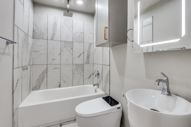 full bathroom featuring toilet, sink, and tiled shower / bath