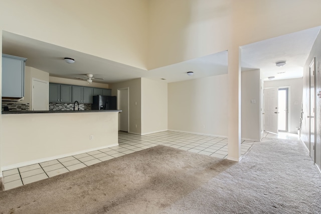 unfurnished living room featuring ceiling fan, light colored carpet, and sink