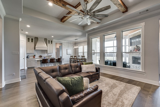 living room with ceiling fan, beamed ceiling, a fireplace, and hardwood / wood-style floors