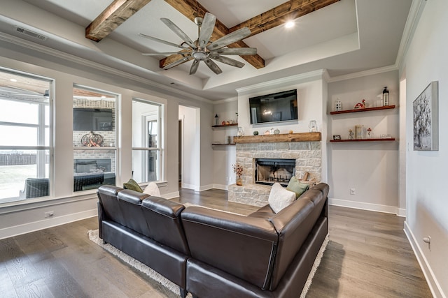 living room with ceiling fan, a stone fireplace, beam ceiling, and wood-type flooring