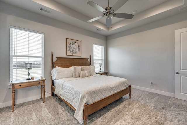 bedroom featuring carpet floors, a raised ceiling, and ceiling fan