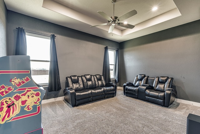 carpeted living room with ceiling fan and a raised ceiling