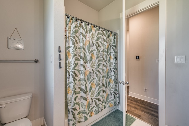 bathroom with curtained shower, toilet, and hardwood / wood-style flooring