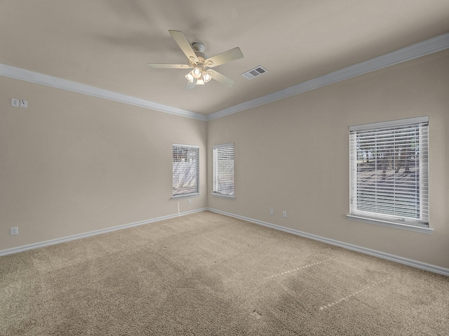 carpeted empty room featuring ornamental molding, visible vents, baseboards, and a ceiling fan