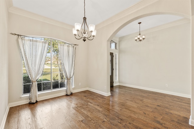 spare room featuring dark wood-type flooring, crown molding, and an inviting chandelier