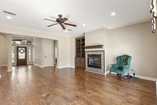 unfurnished living room featuring ornamental molding, dark hardwood / wood-style floors, a fireplace, and ceiling fan