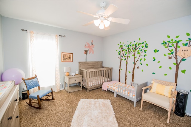 carpeted bedroom with a nursery area and a ceiling fan