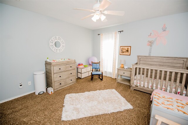 carpeted bedroom featuring a nursery area and ceiling fan