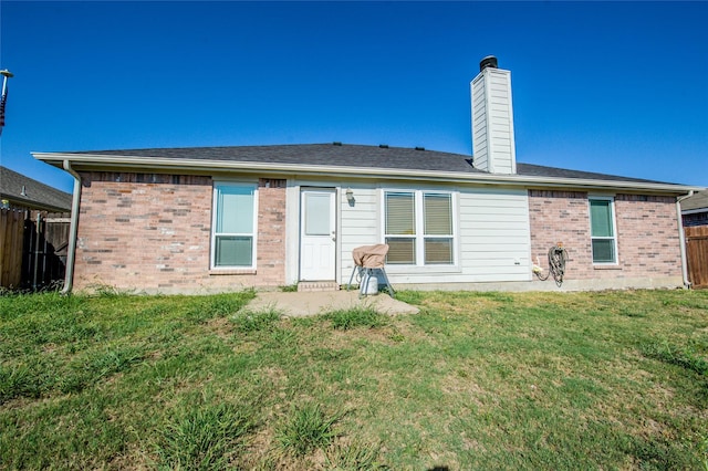 back of property featuring a yard, brick siding, a chimney, and fence