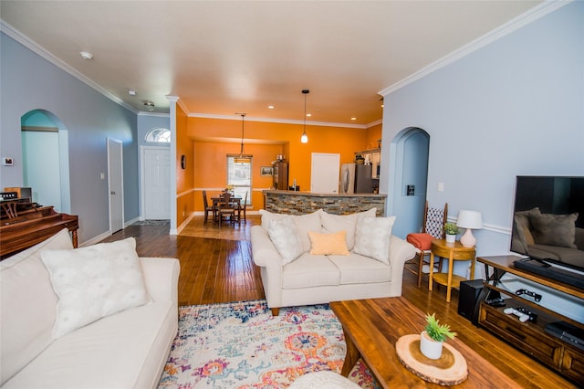 living room featuring dark wood-style floors, arched walkways, recessed lighting, ornamental molding, and baseboards