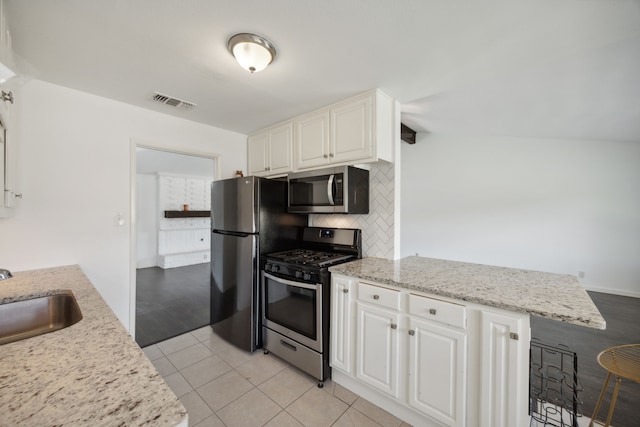 kitchen with white cabinets, backsplash, light tile patterned floors, stainless steel appliances, and sink