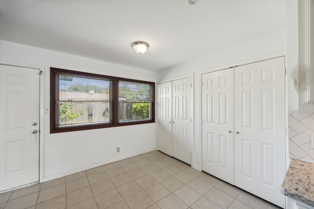 unfurnished bedroom featuring multiple closets and light tile patterned flooring