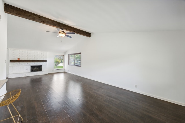 unfurnished living room with lofted ceiling with beams, ceiling fan, dark wood-type flooring, and a brick fireplace