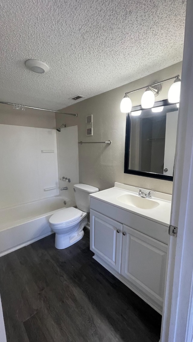 full bathroom with bathtub / shower combination, a textured ceiling, hardwood / wood-style flooring, vanity, and toilet