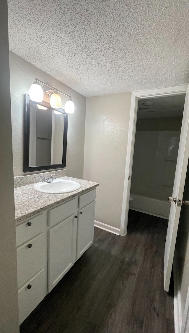 bathroom with a textured ceiling, wood-type flooring, and vanity