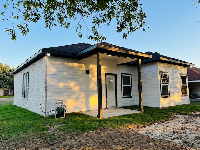 rear view of property with a lawn and a patio