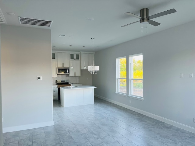 kitchen featuring ceiling fan, white cabinets, decorative light fixtures, a center island with sink, and stainless steel appliances