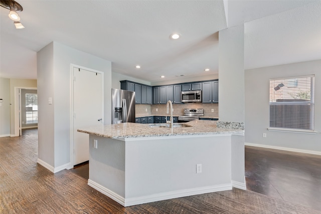 kitchen with light stone counters, appliances with stainless steel finishes, plenty of natural light, and tasteful backsplash