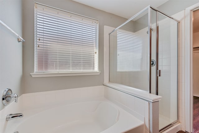 bathroom with wood-type flooring, plus walk in shower, and a wealth of natural light