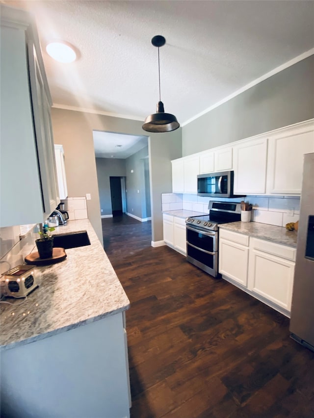 kitchen featuring sink, dark hardwood / wood-style flooring, pendant lighting, white cabinets, and appliances with stainless steel finishes