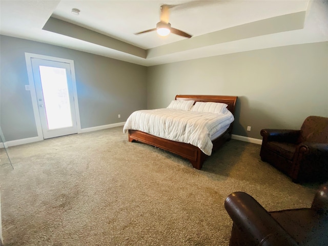 carpeted bedroom featuring ceiling fan and a tray ceiling