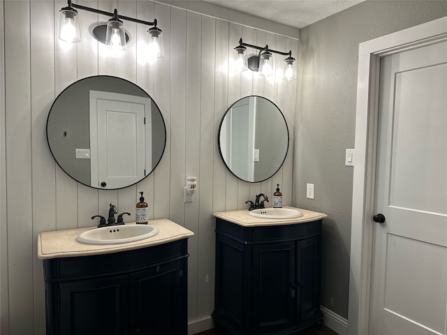 bathroom with wooden walls, vanity, and a textured ceiling