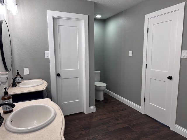 bathroom with hardwood / wood-style floors, vanity, toilet, and a textured ceiling