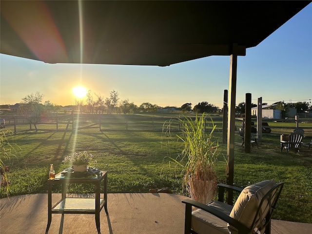 patio terrace at dusk featuring a lawn