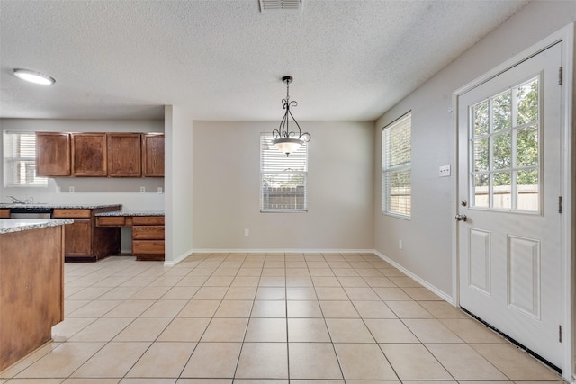 1200 Scenic Hills Dr, Mckinney, TX 75071 - kitchen featuring brown cabinets, light tile patterned floors, a wealth of natural light, and hanging light fixtures