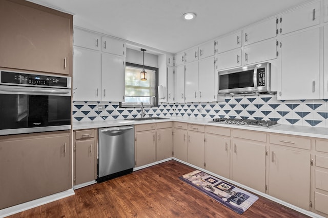 kitchen with white cabinetry, stainless steel appliances, decorative light fixtures, dark hardwood / wood-style floors, and sink