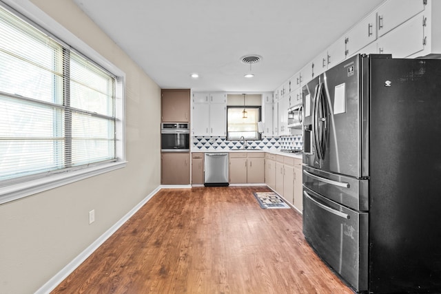 kitchen featuring light hardwood / wood-style floors, sink, white cabinetry, stainless steel appliances, and backsplash