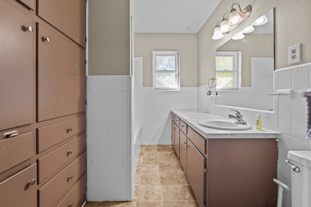 bathroom featuring vanity, tile walls, tile patterned flooring, and a tub to relax in