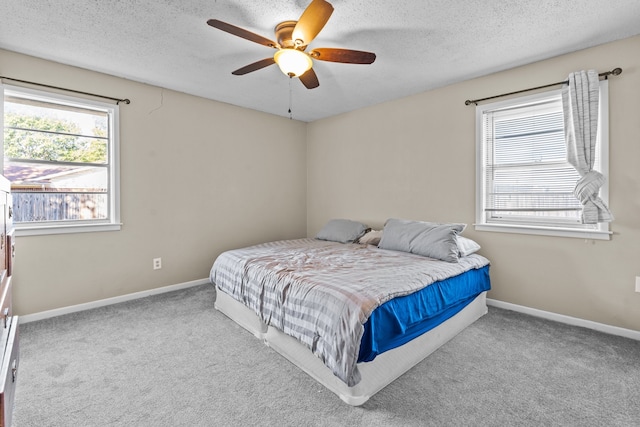 carpeted bedroom featuring ceiling fan and a textured ceiling