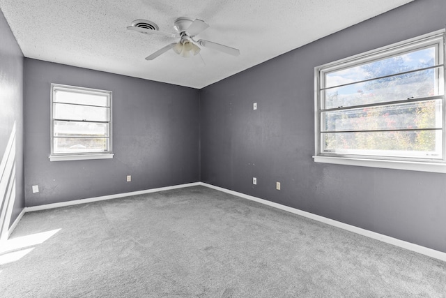 empty room with ceiling fan, a textured ceiling, carpet, and a wealth of natural light