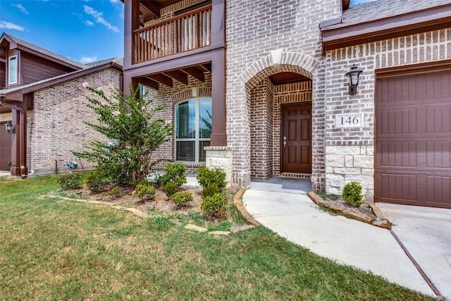 entrance to property featuring a balcony, a lawn, and a garage