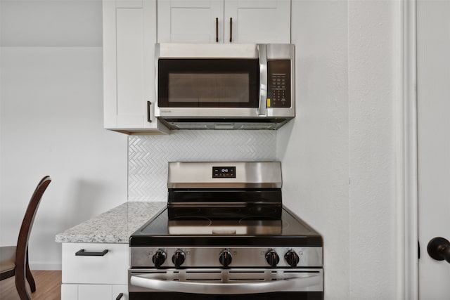 kitchen featuring white cabinets, light stone countertops, stainless steel appliances, and light hardwood / wood-style flooring