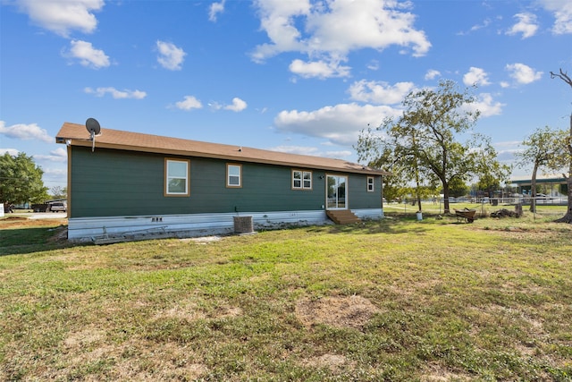 rear view of property with central air condition unit and a lawn